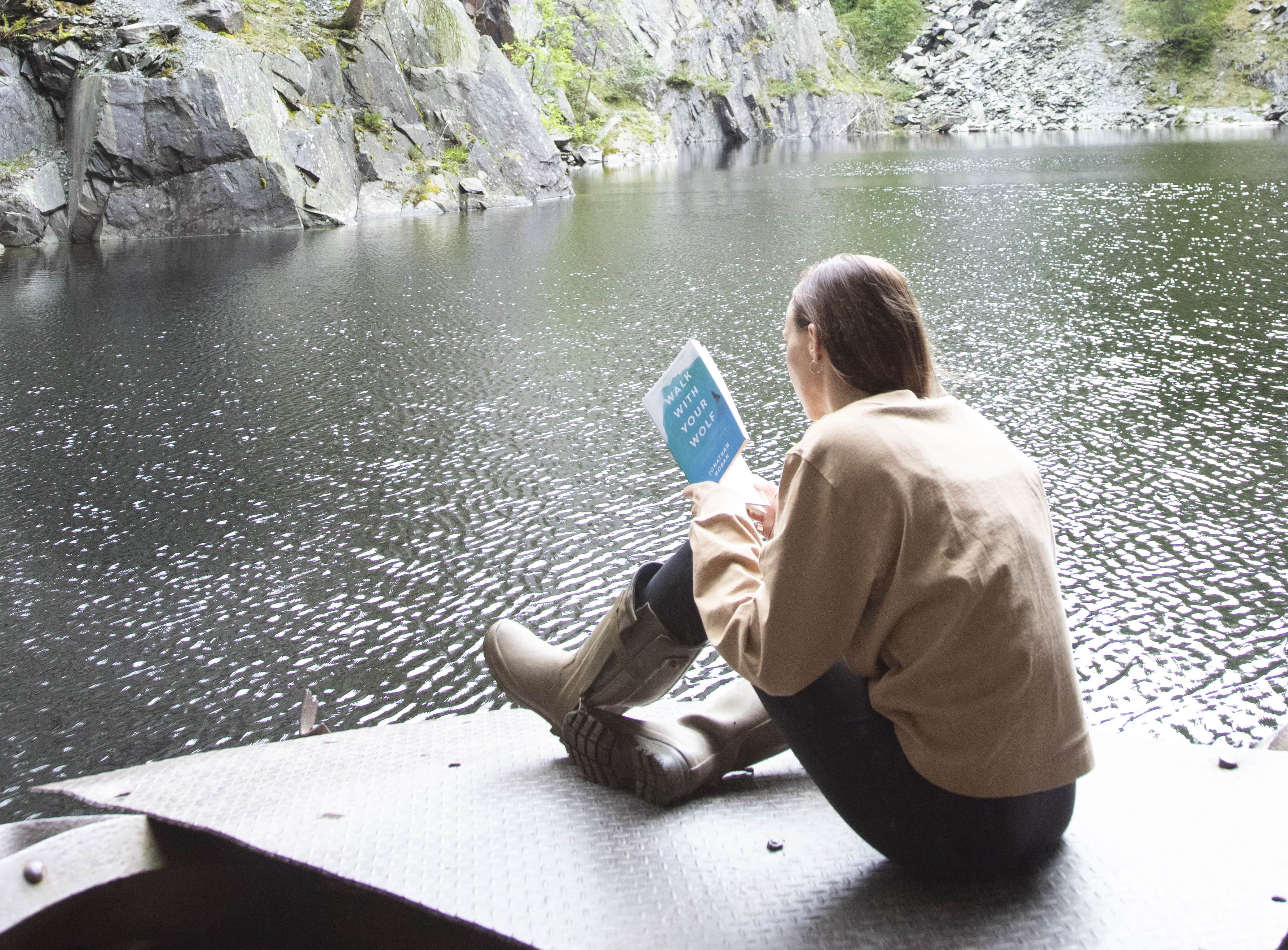 Liz sitting on a bridge staring out to a lake